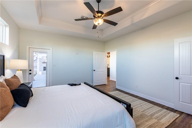 bedroom featuring ceiling fan, dark hardwood / wood-style flooring, a tray ceiling, and multiple windows