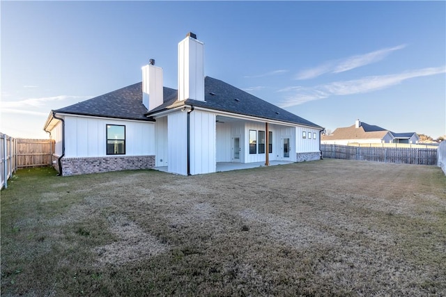 back of house with a patio area and a lawn