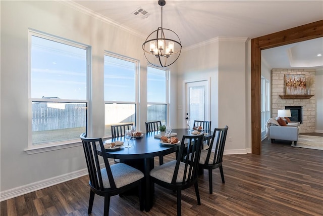 dining area featuring dark hardwood / wood-style floors, ornamental molding, a chandelier, and a fireplace