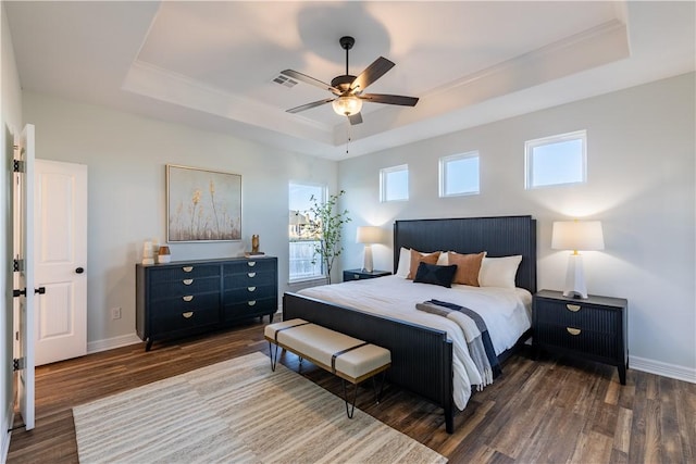 bedroom featuring ceiling fan, dark wood-type flooring, and a tray ceiling