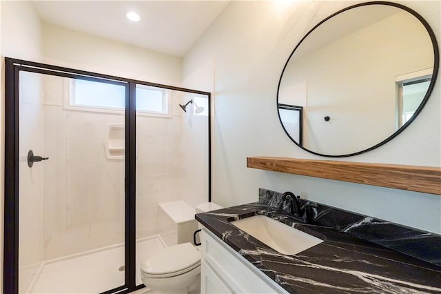 bathroom featuring toilet, a shower with door, and vanity