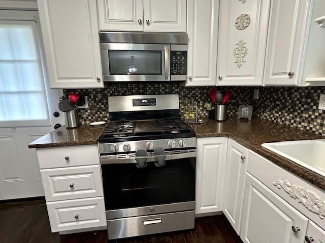 kitchen with white cabinetry, dark wood-type flooring, dark stone countertops, decorative backsplash, and appliances with stainless steel finishes