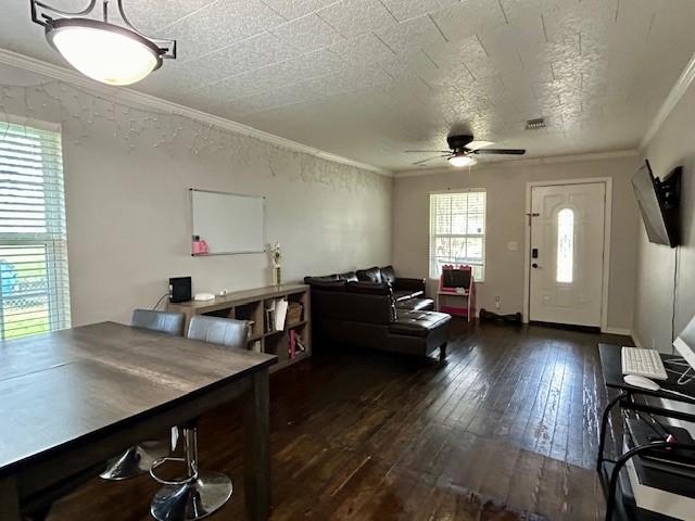 interior space featuring a textured ceiling, ceiling fan, crown molding, and dark wood-type flooring