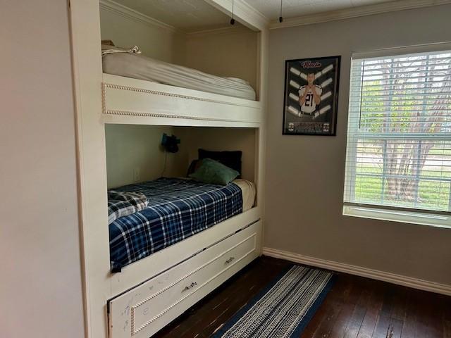 bedroom featuring crown molding and dark wood-type flooring