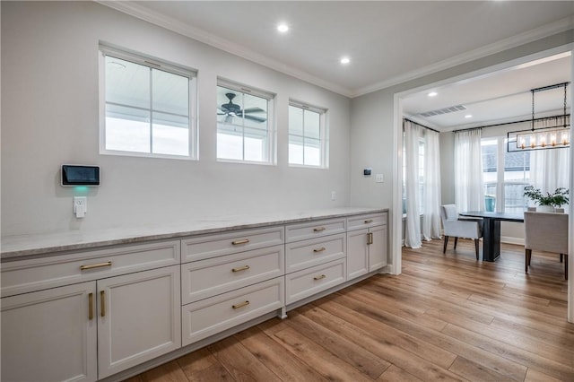 interior space with crown molding, hanging light fixtures, light hardwood / wood-style floors, light stone counters, and white cabinetry