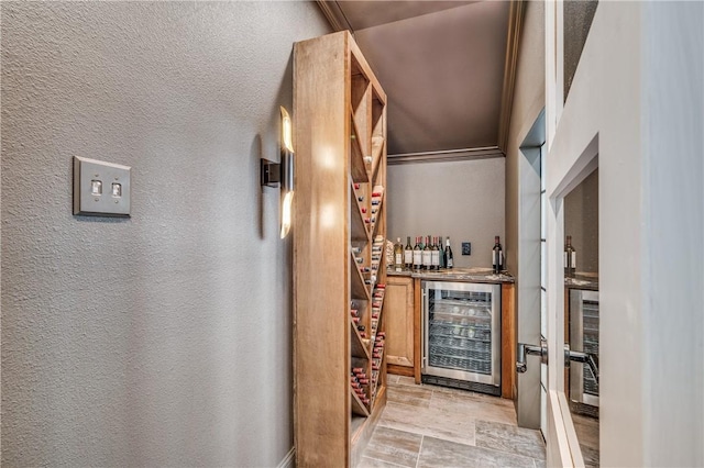 wine area featuring bar, crown molding, and wine cooler