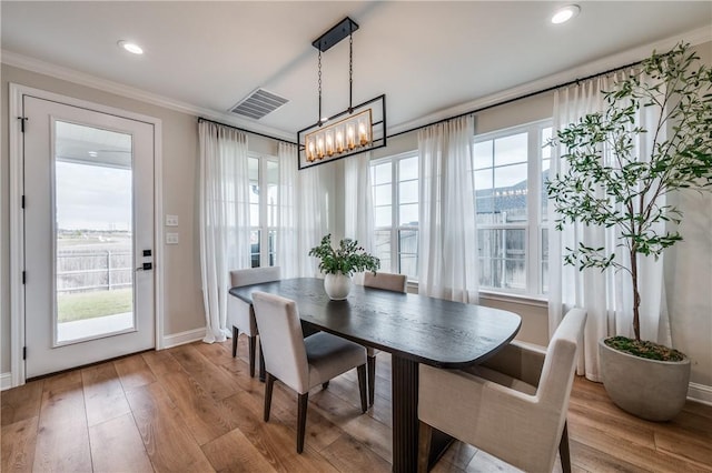 dining area featuring a chandelier, crown molding, a healthy amount of sunlight, and light hardwood / wood-style floors