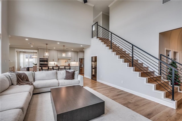 living room featuring a towering ceiling, ornamental molding, and hardwood / wood-style flooring