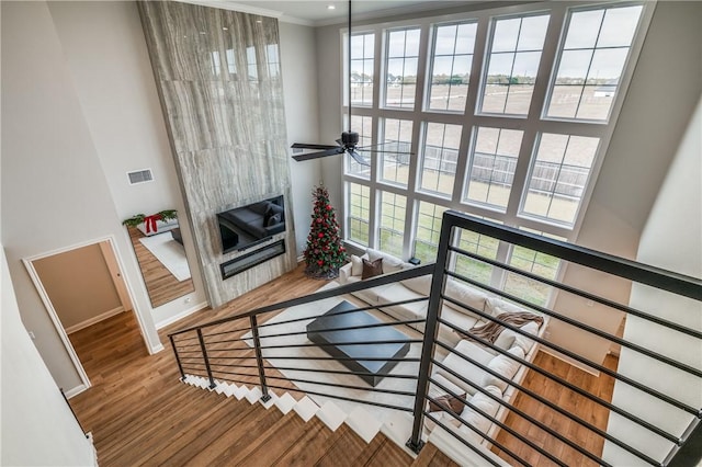 stairway with hardwood / wood-style floors, a wealth of natural light, and ornamental molding