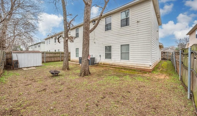 back of house featuring a fenced backyard, an outdoor structure, and a fire pit