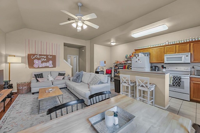 living area featuring lofted ceiling, light tile patterned floors, and a ceiling fan