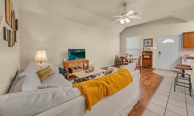 living room with vaulted ceiling, light tile patterned flooring, visible vents, and a ceiling fan