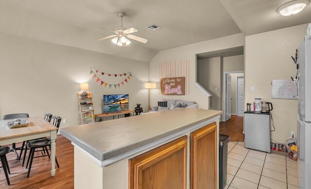 kitchen with visible vents, a ceiling fan, lofted ceiling, a center island, and light countertops