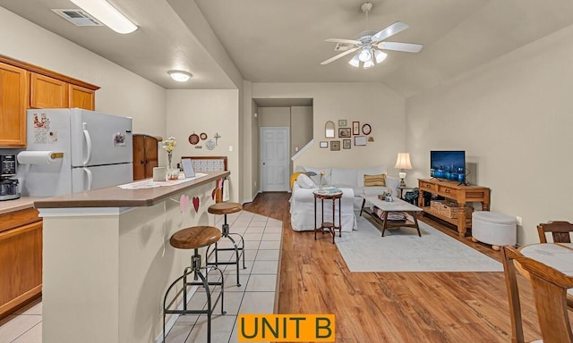 kitchen featuring visible vents, light wood-style floors, freestanding refrigerator, open floor plan, and a kitchen breakfast bar