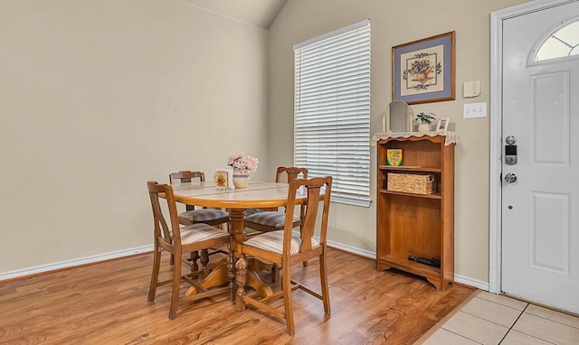 dining space with vaulted ceiling, light wood-style flooring, and baseboards