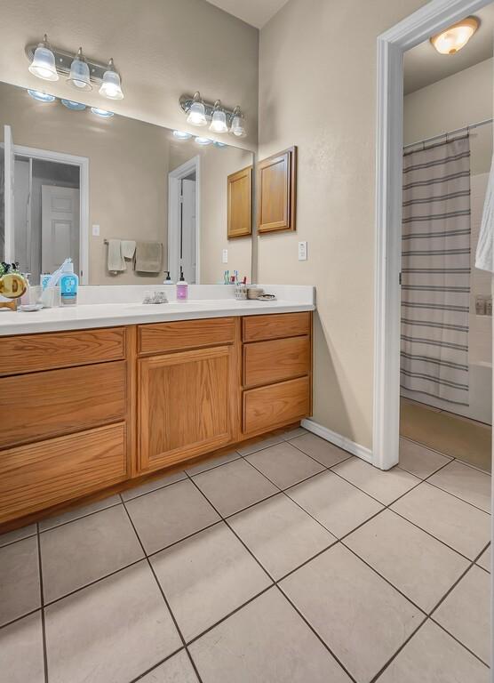 bathroom with a shower with curtain, vanity, baseboards, and tile patterned floors