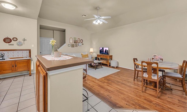 kitchen featuring a center island, brown cabinets, visible vents, ceiling fan, and a kitchen bar