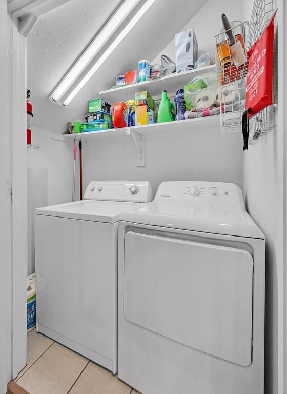 laundry area with laundry area, light tile patterned floors, and washer and clothes dryer