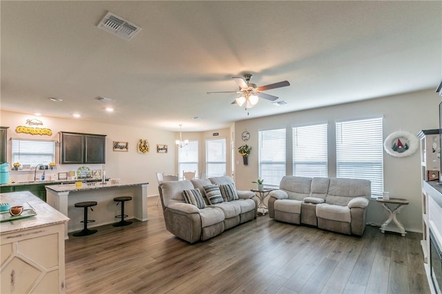 living room featuring hardwood / wood-style floors, ceiling fan with notable chandelier, and sink