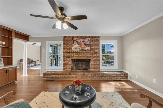 unfurnished living room with decorative columns, a fireplace, dark hardwood / wood-style flooring, and ornamental molding