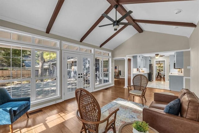 sunroom / solarium with vaulted ceiling with beams, ceiling fan, ornate columns, and french doors