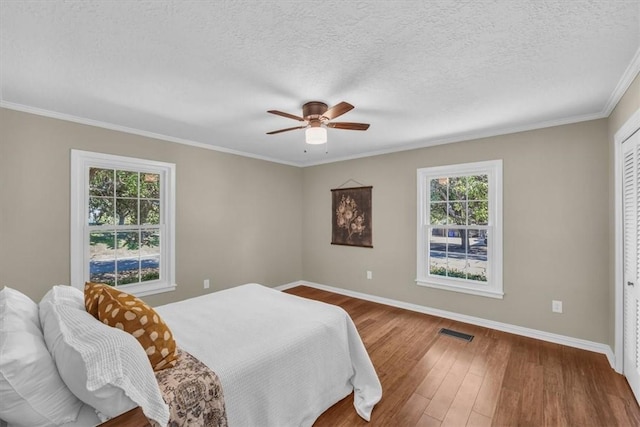 bedroom featuring multiple windows, ceiling fan, hardwood / wood-style floors, and a textured ceiling