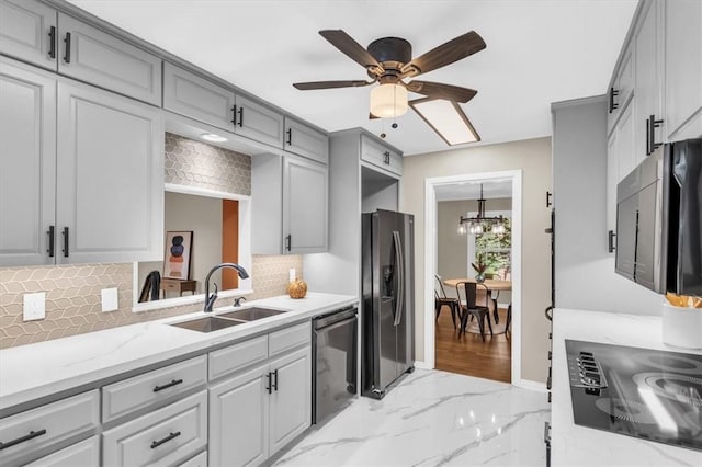 kitchen featuring decorative backsplash, ceiling fan with notable chandelier, sink, and appliances with stainless steel finishes