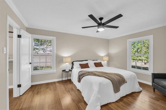 bedroom featuring multiple windows, ceiling fan, wood-type flooring, and ornamental molding