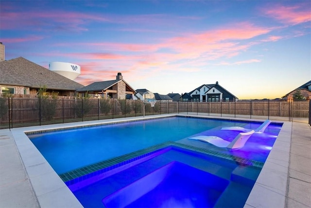 pool at dusk with an in ground hot tub