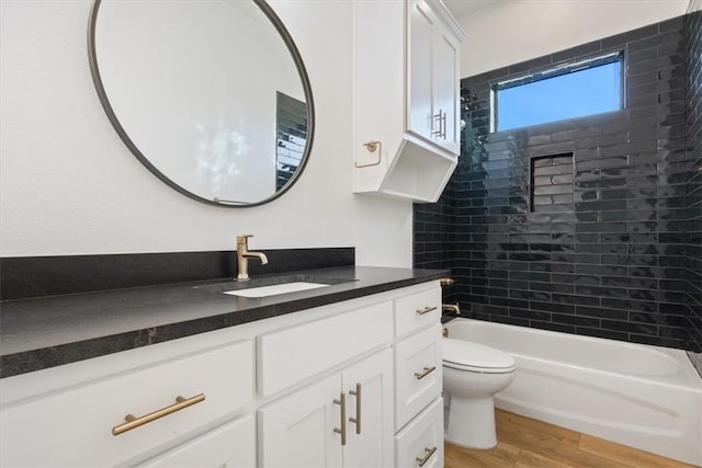 full bathroom featuring hardwood / wood-style floors, vanity, tiled shower / bath combo, and toilet