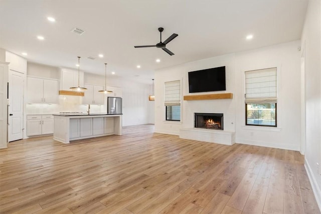 unfurnished living room with ceiling fan, light hardwood / wood-style flooring, and sink