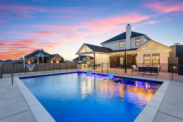 pool at dusk featuring area for grilling and a patio area