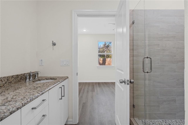 bathroom with a shower with door, vanity, and wood-type flooring