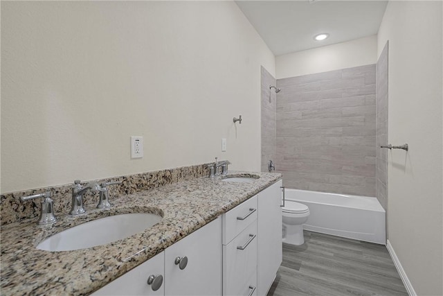 full bathroom featuring tiled shower / bath, vanity, wood-type flooring, and toilet