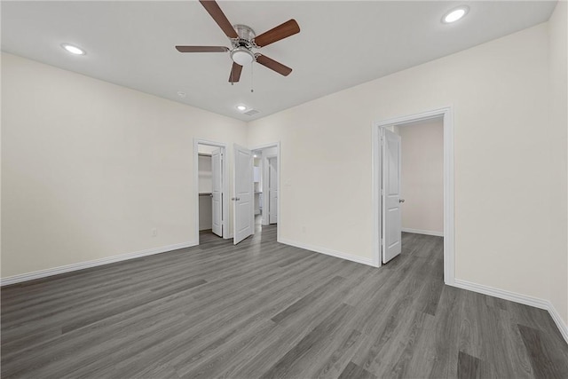 unfurnished bedroom with a walk in closet, ceiling fan, a closet, and wood-type flooring