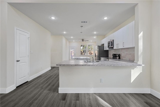 kitchen featuring kitchen peninsula, white cabinetry, dark hardwood / wood-style flooring, and stainless steel appliances