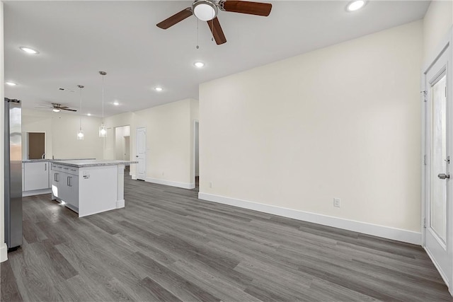 kitchen with pendant lighting, dark hardwood / wood-style floors, stainless steel fridge, ceiling fan, and a kitchen island