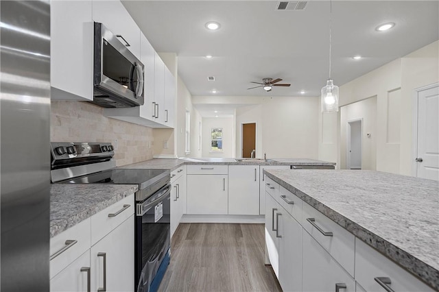 kitchen with white cabinets, ceiling fan, light wood-type flooring, appliances with stainless steel finishes, and decorative light fixtures