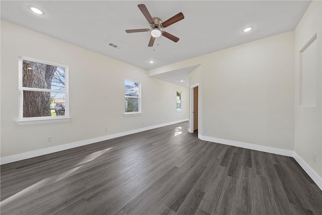 empty room with ceiling fan, a healthy amount of sunlight, and dark hardwood / wood-style flooring