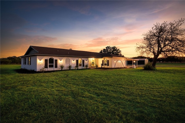 back house at dusk with a garage and a yard