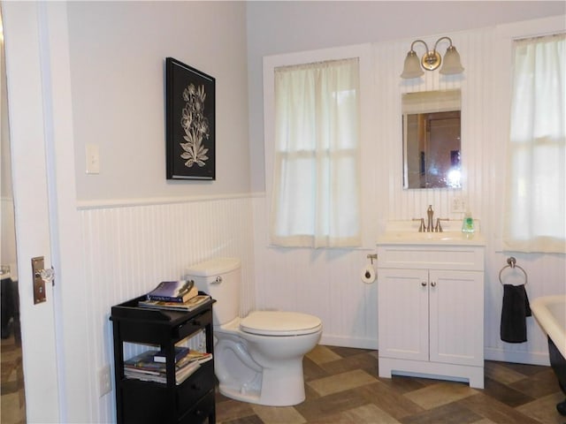 bathroom with a bathing tub, vanity, and toilet