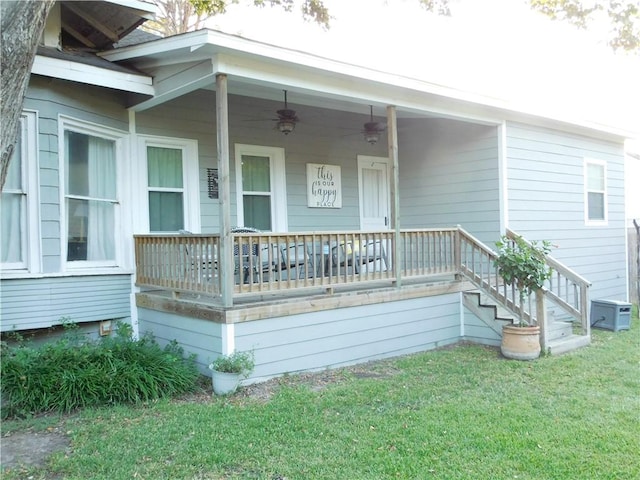 view of exterior entry with covered porch, ceiling fan, and a lawn