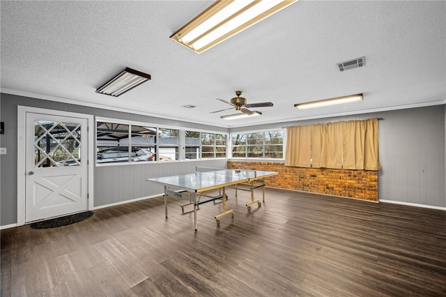 recreation room with dark hardwood / wood-style floors, ceiling fan, ornamental molding, and a textured ceiling