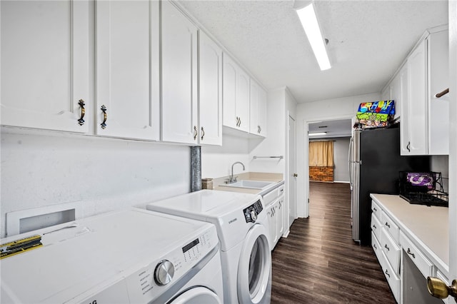 laundry area with washer and clothes dryer, cabinets, dark wood-type flooring, sink, and a textured ceiling