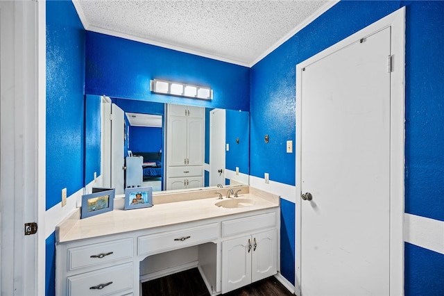 bathroom featuring crown molding, vanity, wood-type flooring, and a textured ceiling