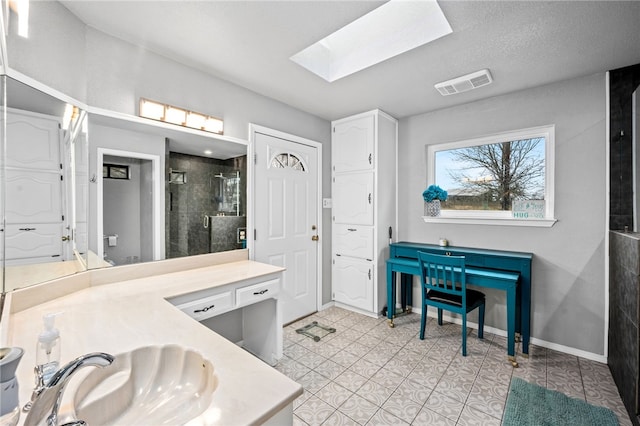 bathroom featuring a skylight, tile patterned flooring, a textured ceiling, vanity, and a shower with shower door