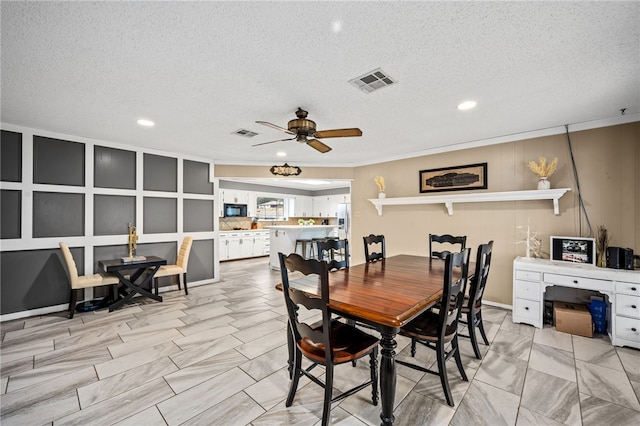 dining space with ceiling fan, ornamental molding, and a textured ceiling