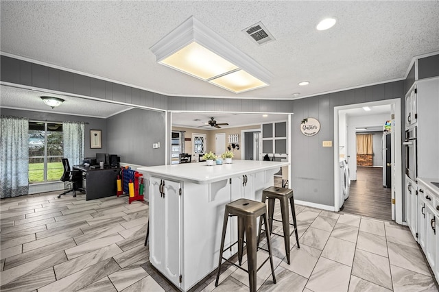 kitchen featuring a kitchen bar, white cabinets, a textured ceiling, and a kitchen island