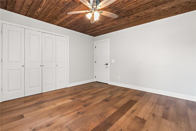 unfurnished bedroom featuring hardwood / wood-style floors, ceiling fan, wood ceiling, and a closet