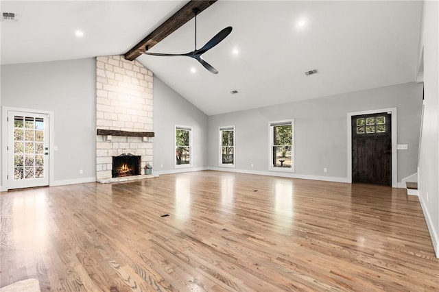 unfurnished living room featuring high vaulted ceiling, a stone fireplace, ceiling fan, beam ceiling, and light hardwood / wood-style floors